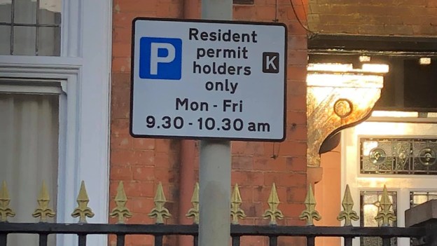 Resident permit parking sign on street furniture in Clarendon Park saying "Resident permit holders only. Zone K. Mon-Fri 9.30-10.30am"